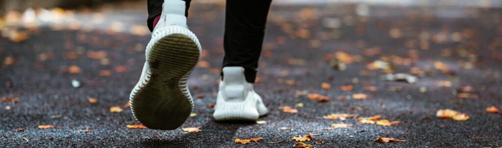 Legs of anonymous person in white sneakers and black leggings running on sidewalk