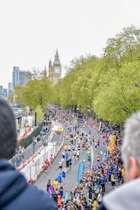 Runners and spectators attend a marathon near Big Ben in London, UK, showcasing urban energy.